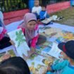 Pemandangan salah satu guru mengajar anak anak membaca di   taman.