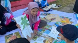 Pemandangan salah satu guru mengajar anak anak membaca di   taman.