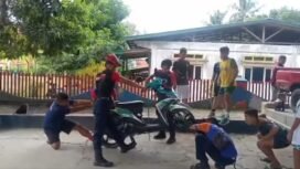 sejumlah petugas Damkar mencoba mengeluarkan ular kobra yang masuk body motor salah satu warga,