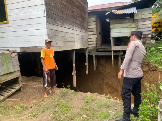 
					Polisi melihat kondisi rumah Nono, warga Desa Bulan Bulan, Kecamatan Lumbis. Pasca terbentuk lubang secara tiba tiba rumah Nono terancam ambruk.