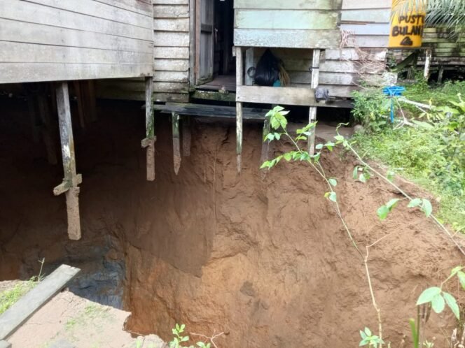 
					Rumah milik warga bernama Nono di Desa Bulan Bulan, Kecamatan Lumbis. Rumah tergantung akibat lubang yang tiba tiba terbentuk saat hujan deras mengguyur, Kamis (3/7/2025) malam.