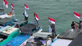 Prajurit TNI AL memasangkan bendera merah putih di sejumlah perahu nelayan di perairan tapal batas RI - Malaysia di Karang Unarang jelang HUT 80 RI. Dok.Penerangan LANAL Nunukan.