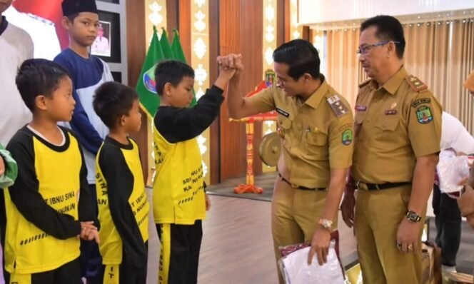 
					Bupati Nunukan, Irwan Sabri melakukan tos dengan anak sekolah saat membagikan seragam gratis secara simbolis yang menjadi implementasi salah satu program unggulan Pemerintah, Selasa (26/8/2025).