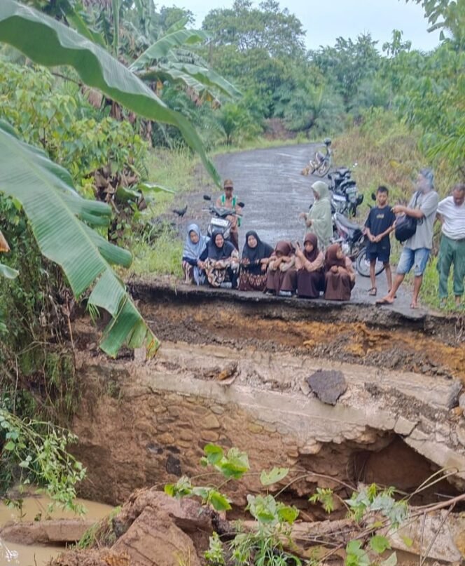 
					Sejumlah murid madrasah terduduk dan melamun melihat puing jembatan menuju sekolahnya ambruk akibat banjir, Rabu (5/11/2025) malam. Dok.Andre Pratama.