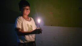 Ilustrasi : Anak kecil menyalakan lilin saat lampu PLN mati.