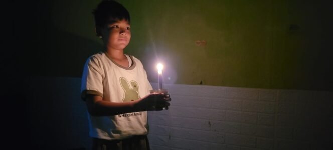 
					Ilustrasi : Anak kecil menyalakan lilin saat lampu PLN mati.