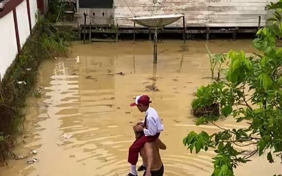 Murid SD 004 Sei Limau Sebatik dipanggul kakeknya dan diantar ke sekolah. Hujan deras yang mengguyur Pulau Sebatik semalaman mengakibatkan sebagian besar wilayah Sebatik kebanjiran. Dok.Ismail.