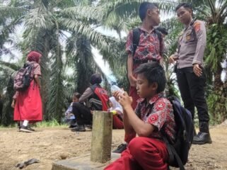 Sejumlah anak anak TKI Malaysia, buruh perkebunan kelapa sawit yang bersekolah di Sebatik. Mereka beristirahat di patok batas negara dan masih setengah jalan menuju mess di Malaysia.